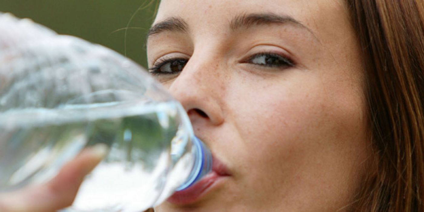 Junge Frau trinkt aus Wasserflasche.