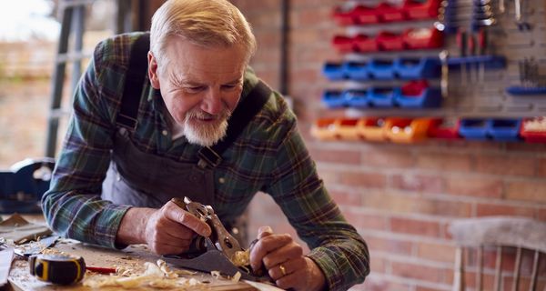 Älterer Mann, macht Holzarbeiten.