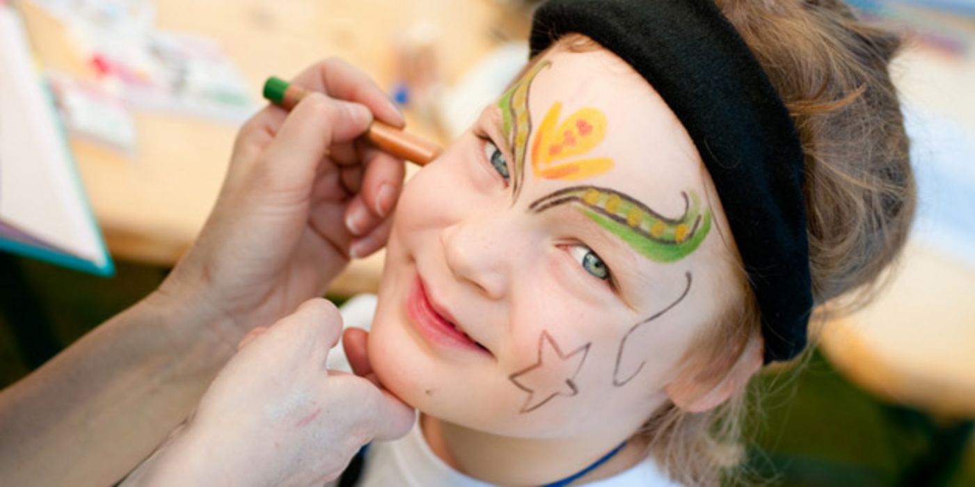 Kindergesicht wird für den Fasching geschminkt