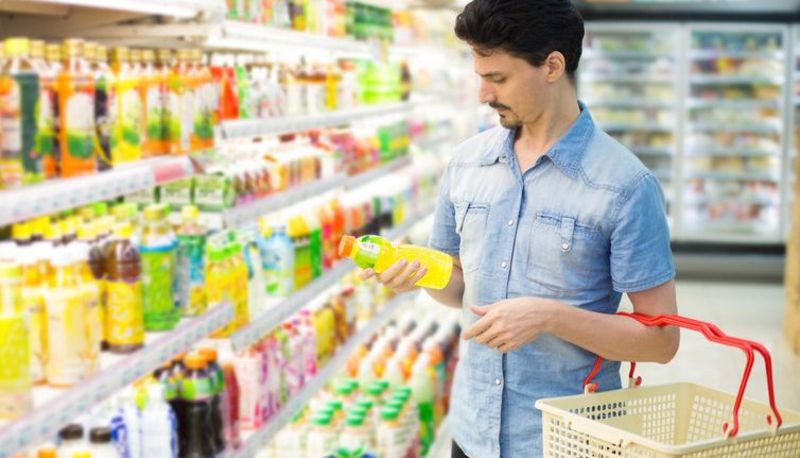 Ein Mann mittleren Alters steht vor einem Kühlregal im Supermarkt.