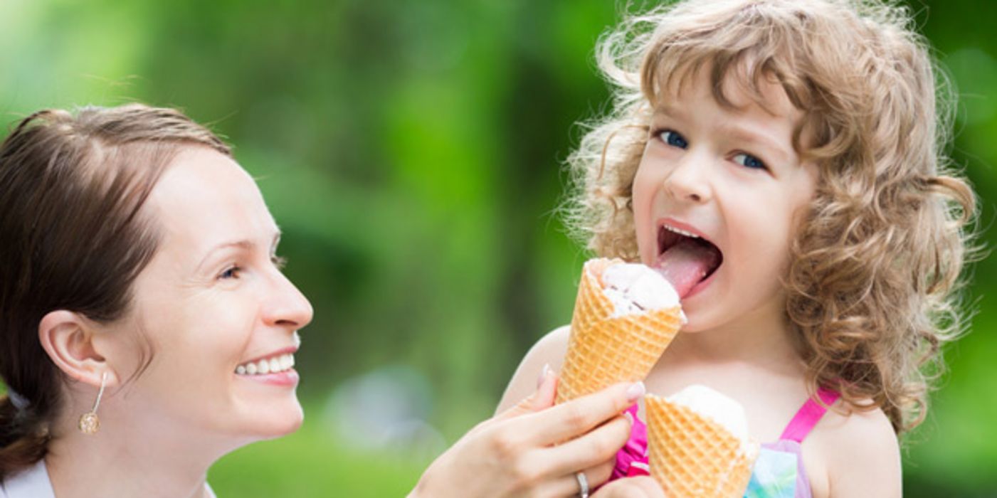 Mutter und Tochter an einem Sommertag, Mädchen isst eine Waffel mit Eis.