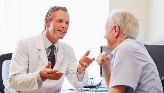 Arzt und Patient unterhalten sich. Sie wirken gutgelaunt.