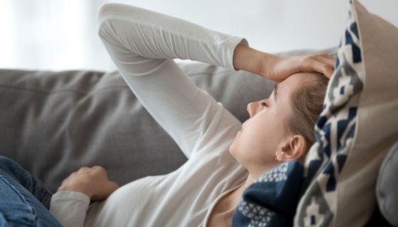 Frau, liegt erschöpft im Bett.