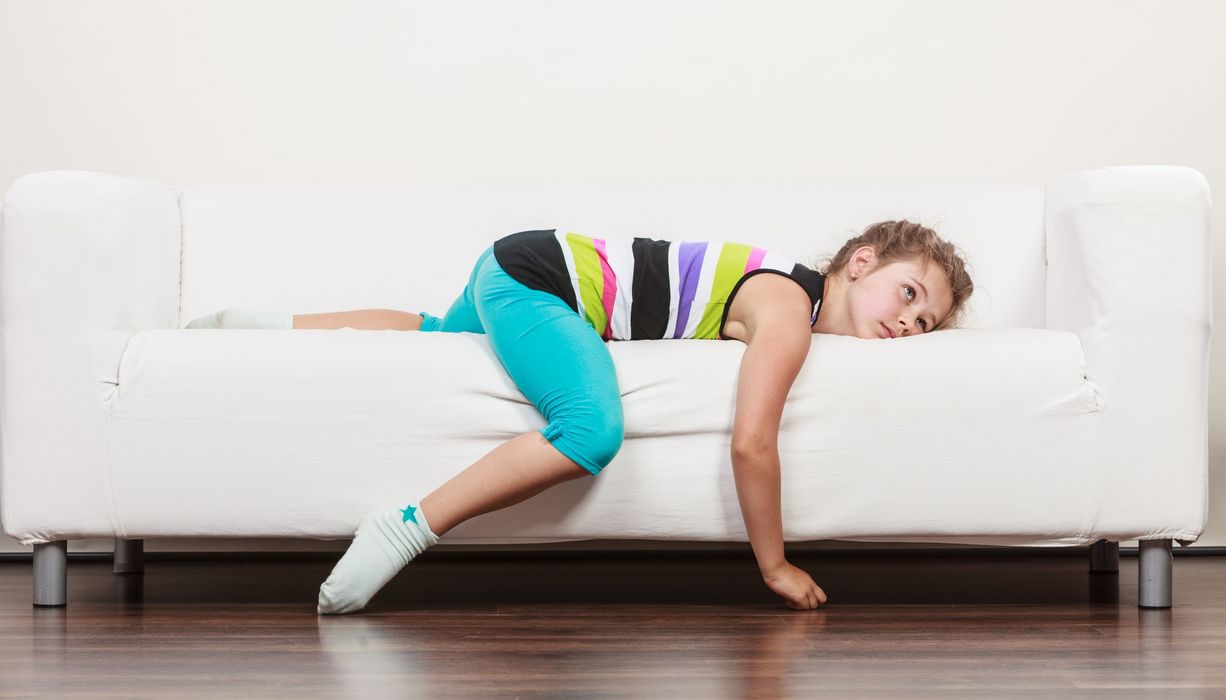 Mädchen, liegt gelangweilt und unruhig auf der Couch.