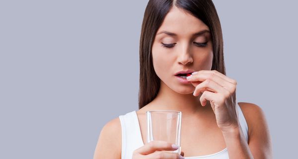 Frau schluckt Tablette.