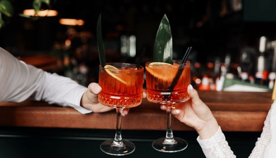 Mann und Frau, stoßen mit einem Cocktail an.