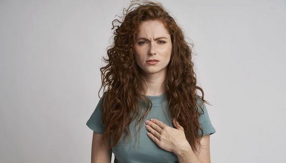 Frau fasst sich ans Brustbein.