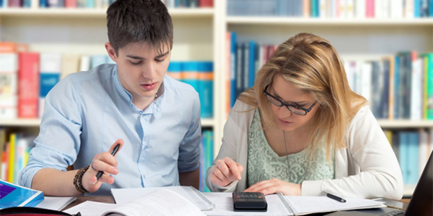 Teenager bei Mathe-Hausaufgaben vor Bücherwand