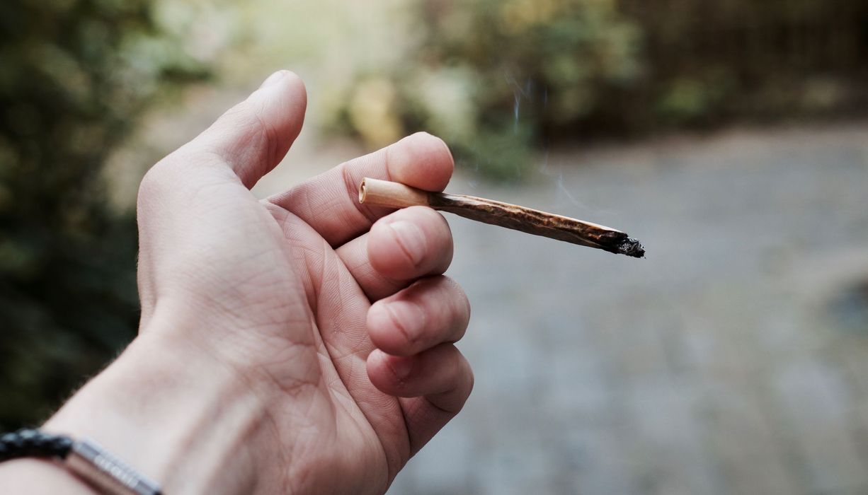 Mann, hält einen Joint in der Hand.