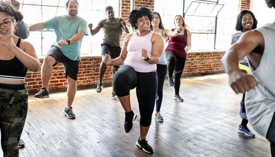 Dicke und dünne Frauen und Männer unterschiedlichen Alters strahlen bei einem Sportkurs Freude aus.
