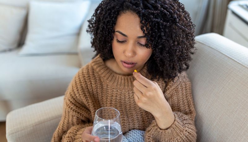 Junge Frau nimmt eine Tablette ein.