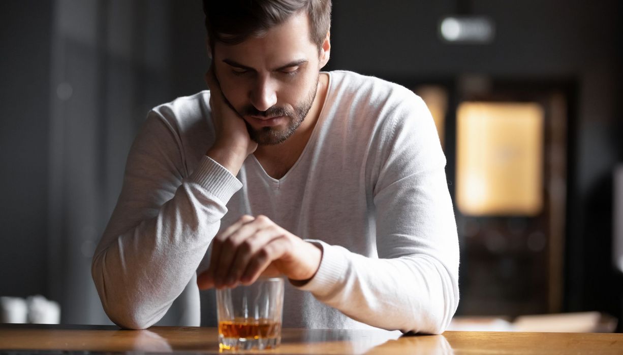 Mann sitzt vor einem Whiskeyglas.