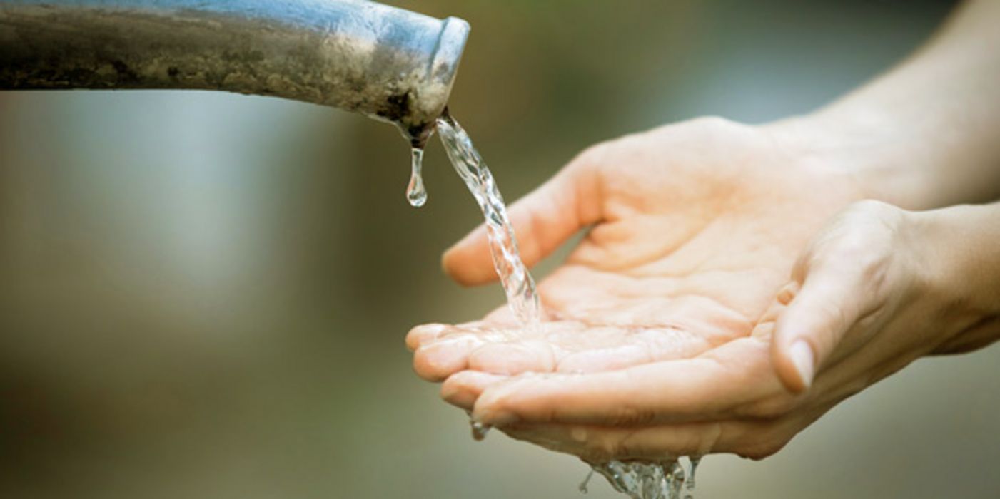 Zwei Hände unter einem Wasserstrahl