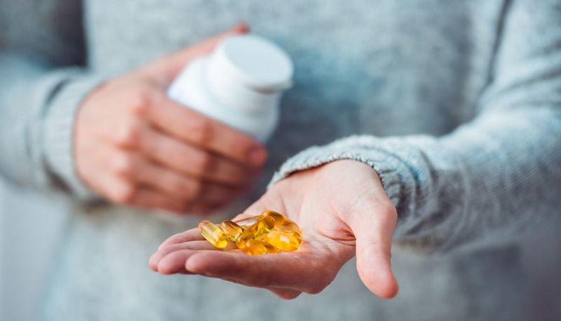 Frau, hält eine Dose in der einen Hand und Tabletten in der anderen Hand.