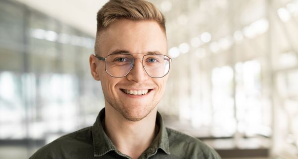 Junger Mann mit Brille blickt direkt den Betrachter direkt an.