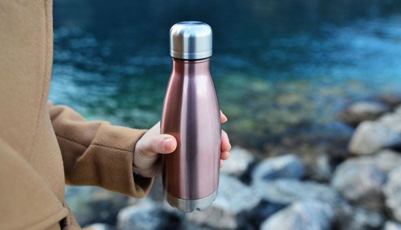 Frau, hält eine Flasche aus Edelstahl in der Hand.