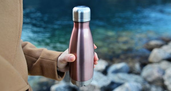 Frau, hält eine Flasche aus Edelstahl in der Hand.