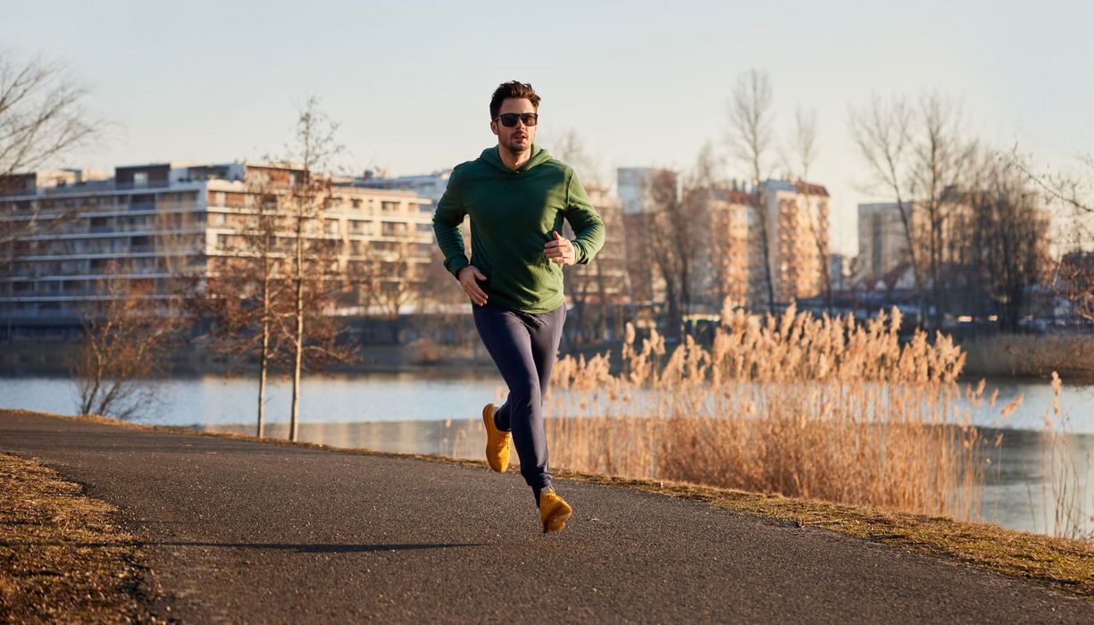 Jogger läuft an winterlichem Fluss.