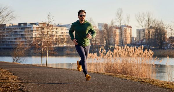 Jogger läuft an winterlichem Fluss.