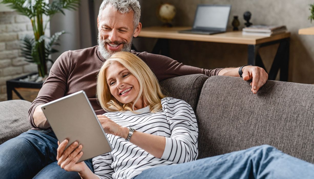 Frau und Mann, ca. 55 Jahre alt, liegen zusammen auf der Couch.