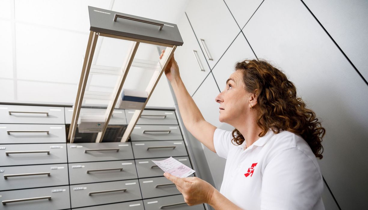 Apothekerin vor leerer Schublade mit Medikamenten.