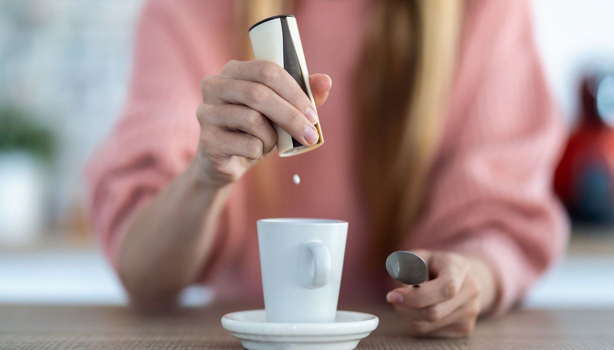 Frau süßt ihren Kaffee mit Süßstoff.