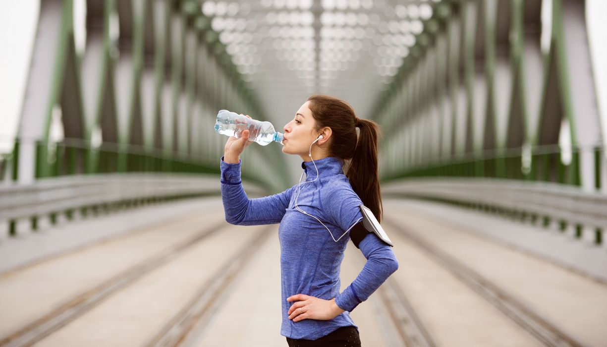 Sportlerin trinkt aus Plastikflasche.