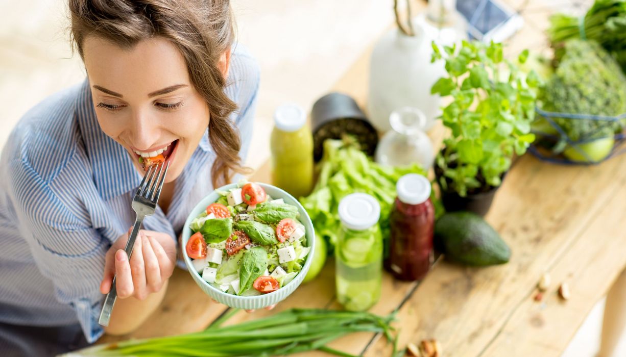 Junge Frau, isst eine Schüssel mi Salat.