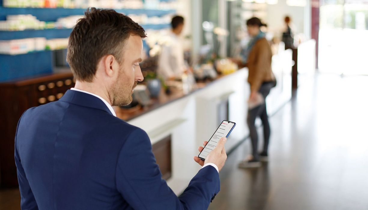 MAnn schaut in der Apotheke auf sein Smartphone.