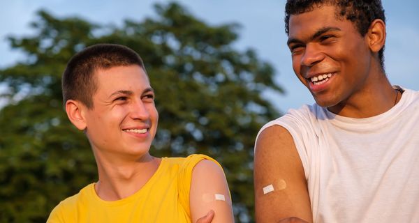 Zwei Jugendliche mit Pflastern auf den Oberarmen.