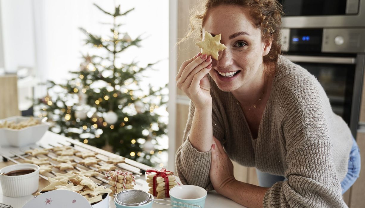 Junge Frau, hält sich einen Weihnachtskeks vor ein Auge.