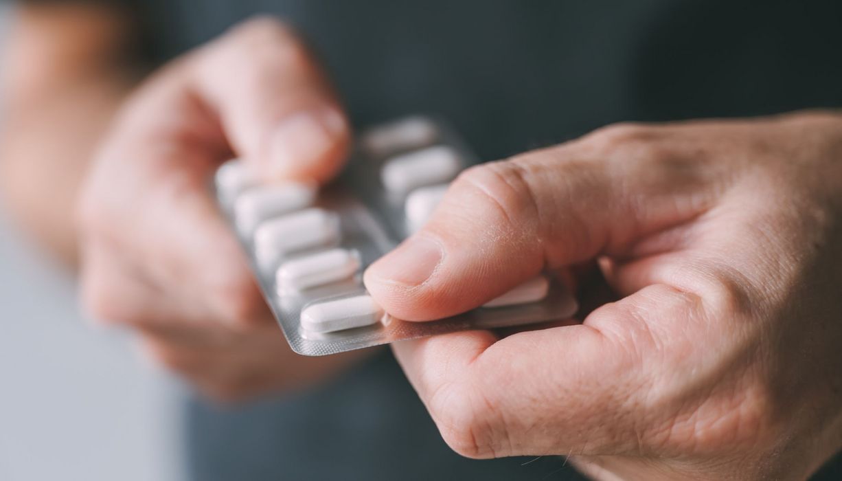 Mann, hat einen Blister mit Tabletten in der Hand.