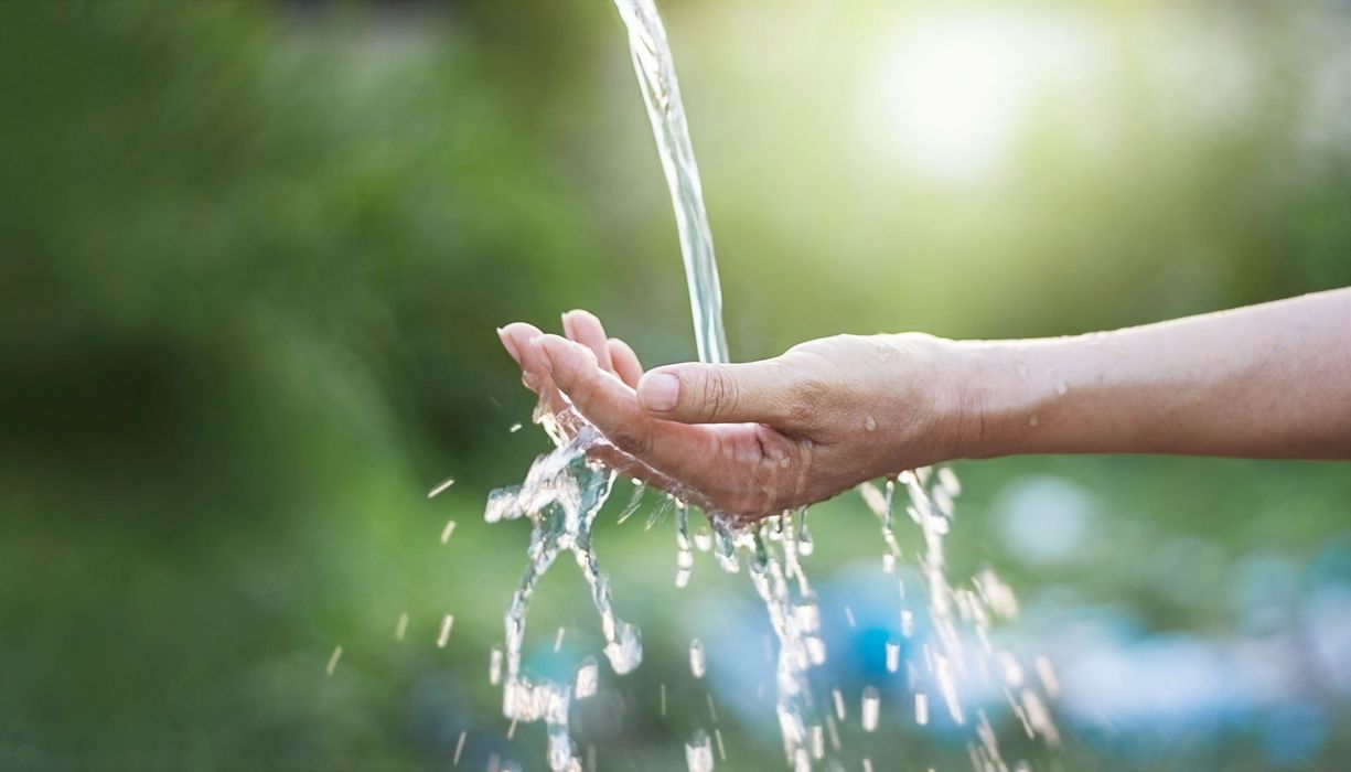 Wasserstrahl, fließt auf eine ausgestreckte Hand.