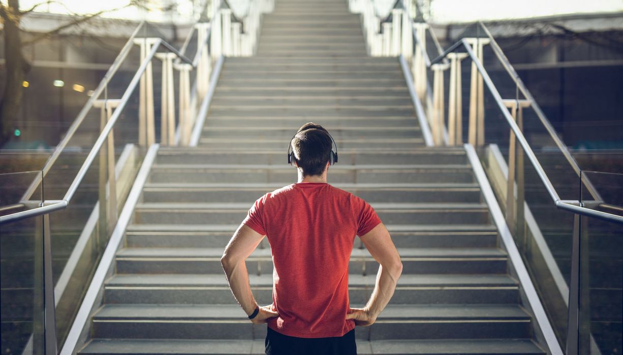 Junger Mann, steht vor einer Treppe.