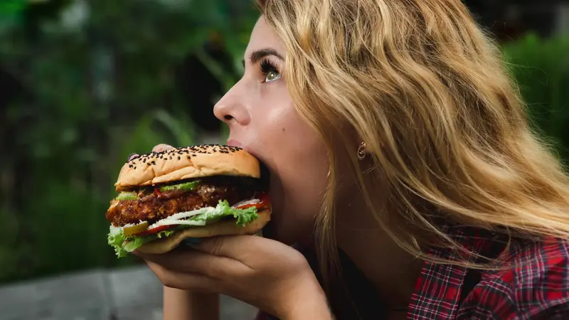 Frau isst Hamburger.