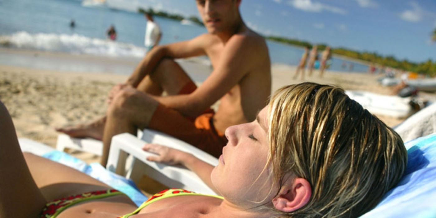 Frau liegt am Strand in der Sonne.