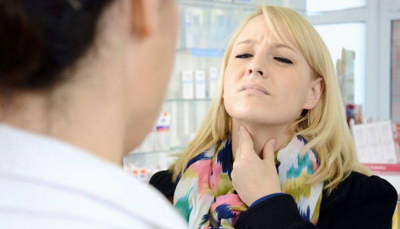 Junge Frau mit Halsschmerzen in der Apotheke