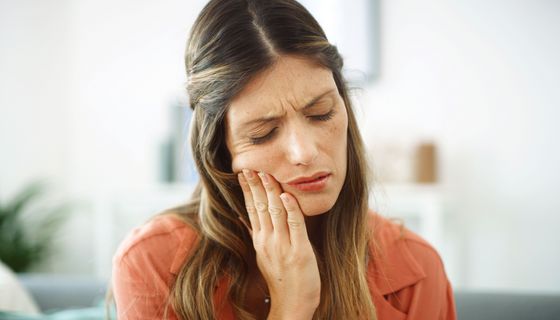 Eine Frau schaut unzufrieden, drückt sich auf die Hand auf die Wange.