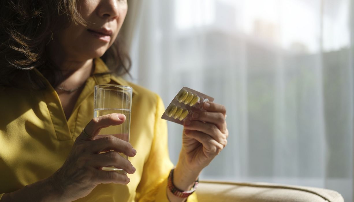 Frau mit Tabletten in der Hand.