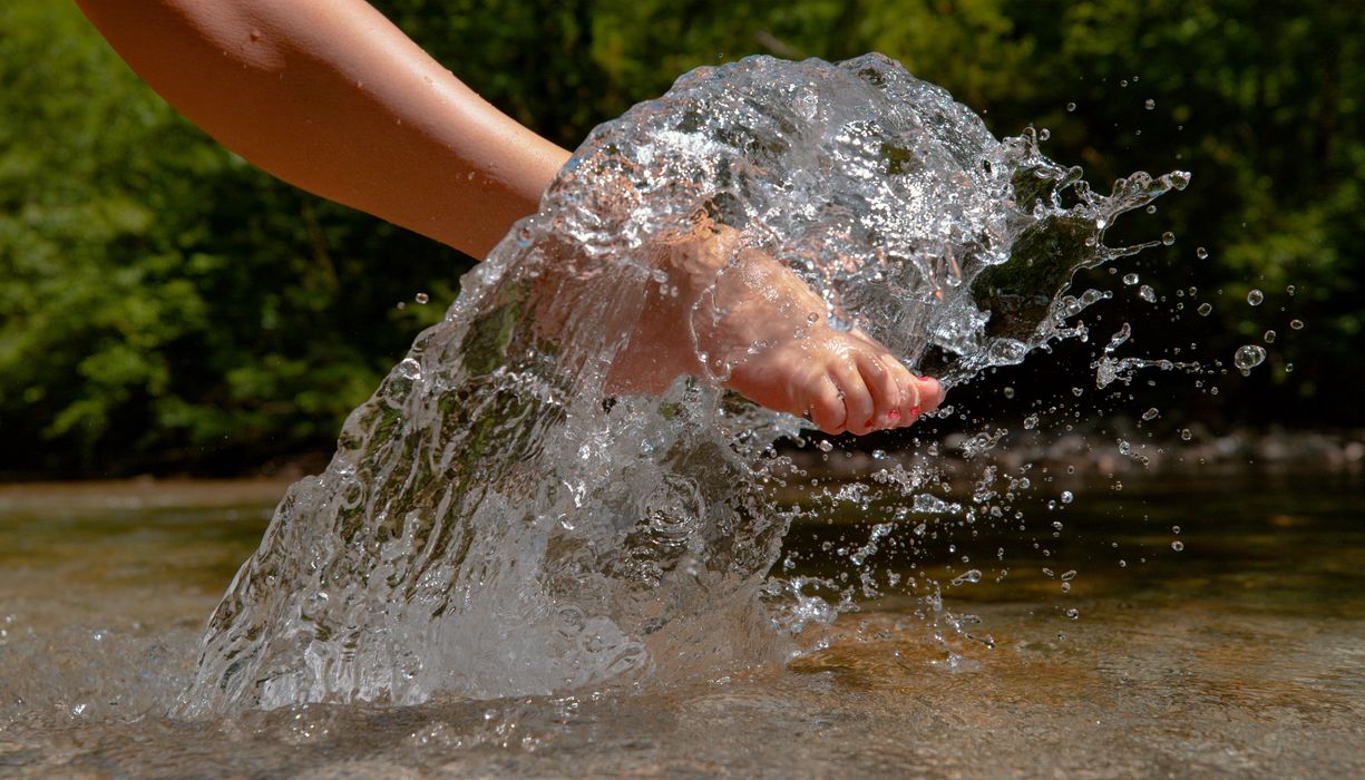 Frau, hält ihren Fuß ins Wasser.