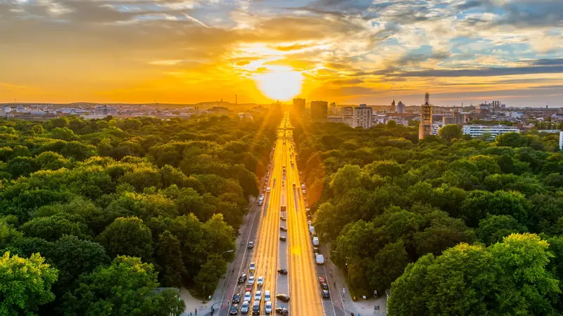 Sonnenuntergang hinter einer Stadt mit vielen Bäumen.