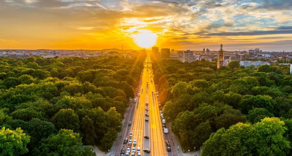 Sonnenuntergang hinter einer Stadt mit vielen Bäumen.