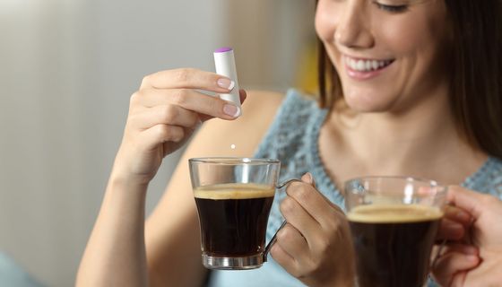Junge Dame macht sich Süßstoff in den Kaffee