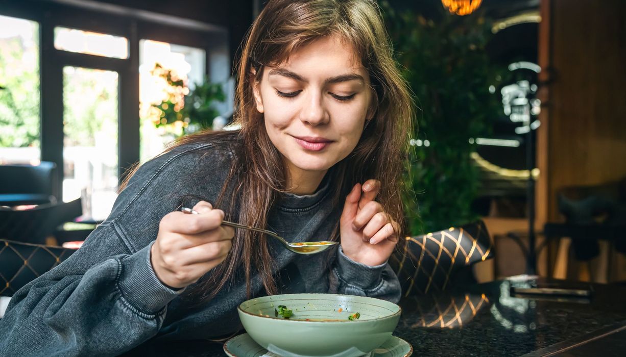 Junge Frau, löffelt Suppe.