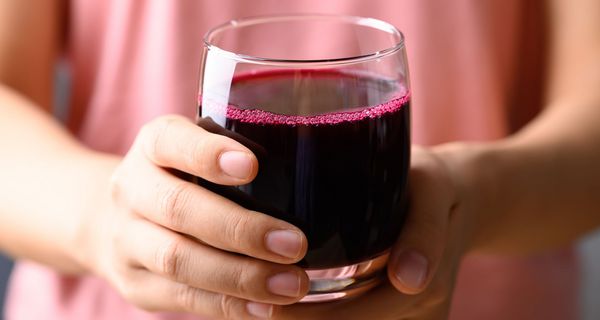 Frau hält ein Glas mit Rote-Bete-Saft.