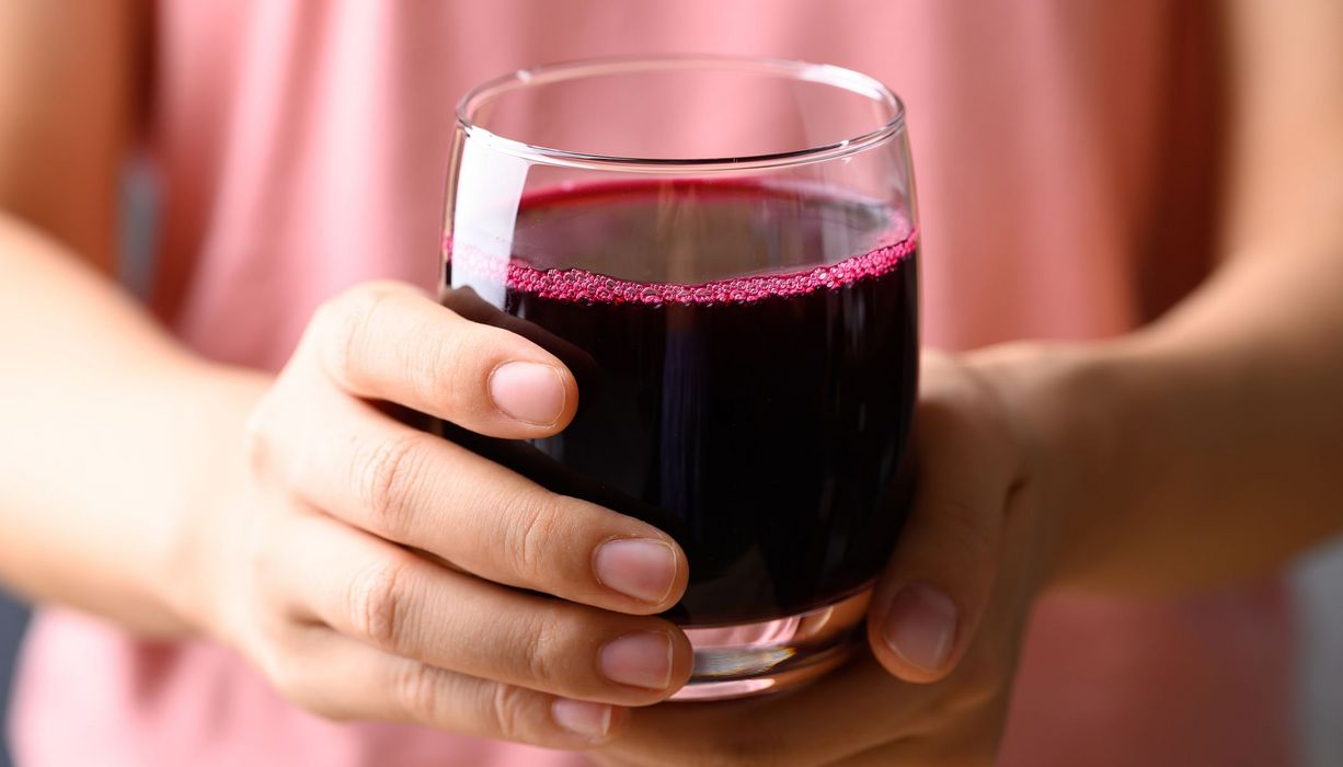 Frau hält ein Glas mit Rote-Bete-Saft.