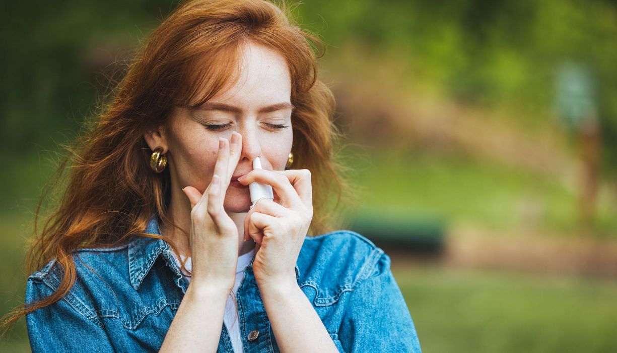 Junge Frau, nutzt Nasenspray.