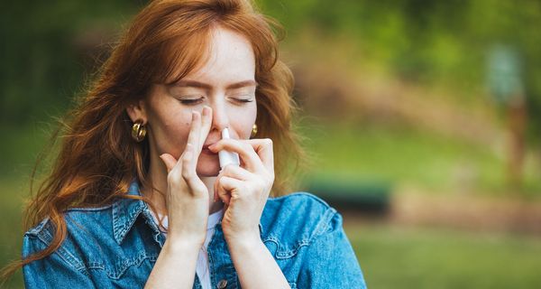 Junge Frau, nutzt Nasenspray.