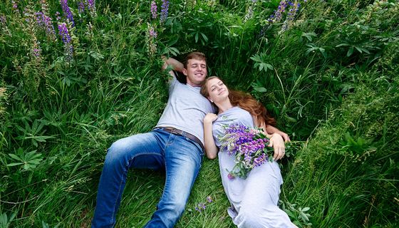 Junges Paar liegt in einer Blumenwiese.