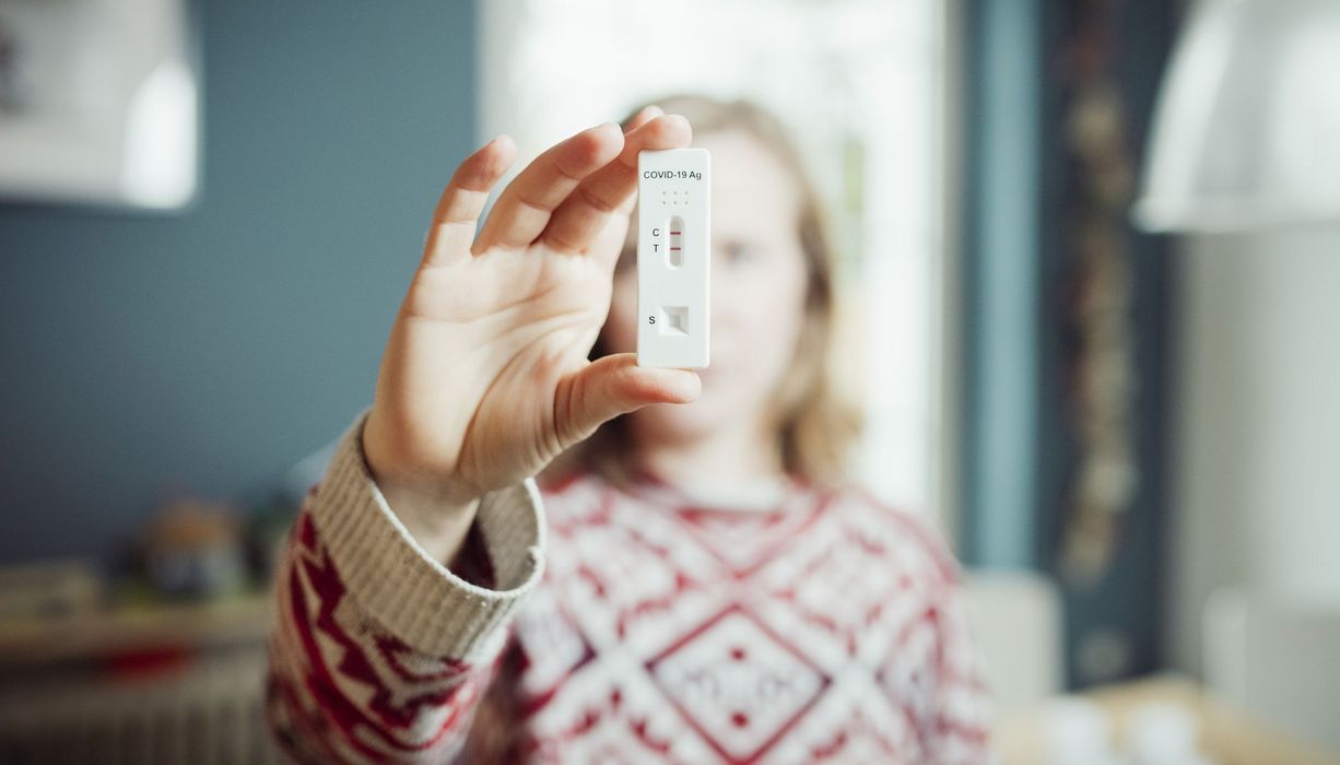 Frau, hält positiven Schnelltest in die Kamera.